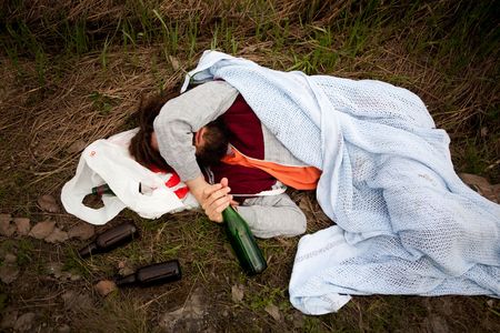 A homeless drunk person laying by the edge of the roadの写真素材
