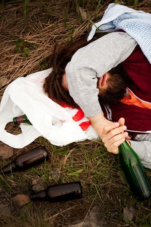 A drunk person sitting in a ditch with a wine bottleの写真素材