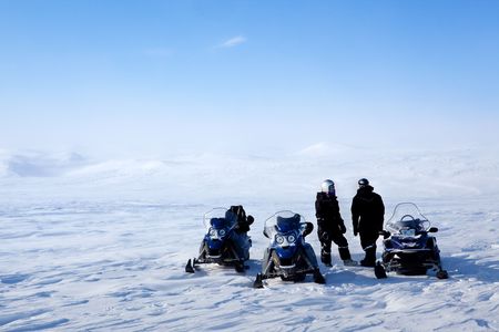 A barren winter landscape with a group of people on a snowmobile expeditionの写真素材