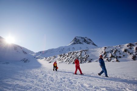 Three people on a short mountain trek, against a beautiful winter landscapeの写真素材
