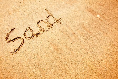 The word sand written in the sand at a beach - background textureの写真素材