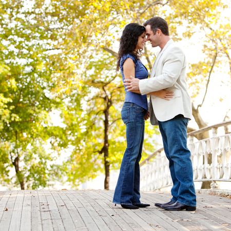 A happy couple in the park looking at the camera and huggingの写真素材