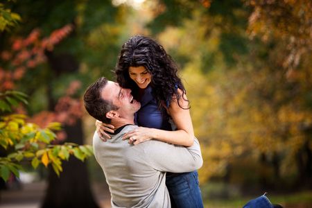 An excited couple giving eachother a big hug in a parkの写真素材