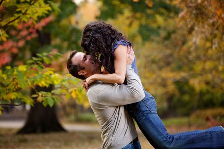 A man giving a woman a big hug in a parkの写真素材