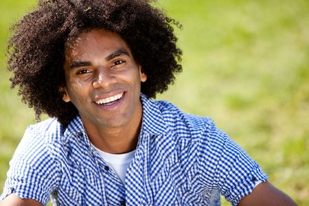 Young man smiling at camera in a park. Horizontally framed shot.の写真素材