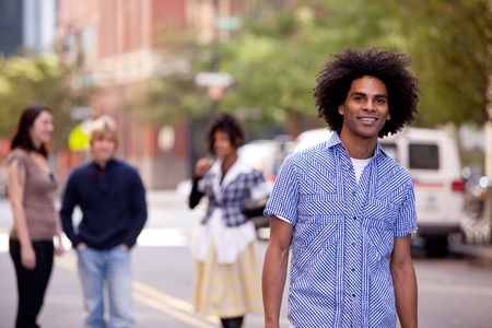 Four people on city street with young male as focus. Horizontally framed shot.の写真素材