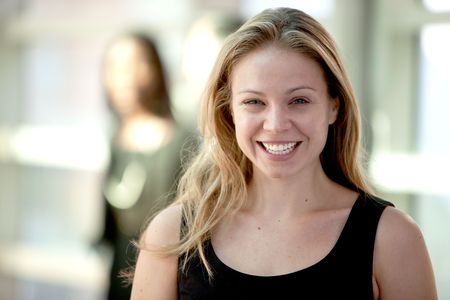 Attractive young blonde woman smiling while looking at camera with woman in background. Horizontally framed shot.の写真素材