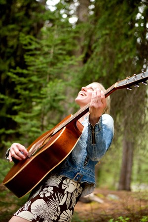 A woman singing freely in the forest with a guitar - sharp focus on guitar
の写真素材