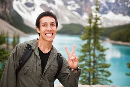 Happy male hiker showing you the victory sign against natural backgroundの写真素材