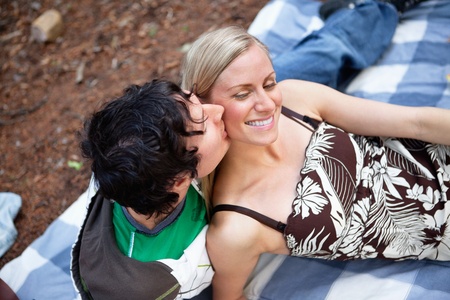 Top view of romantic young guy kissing happy female while on picnicの写真素材