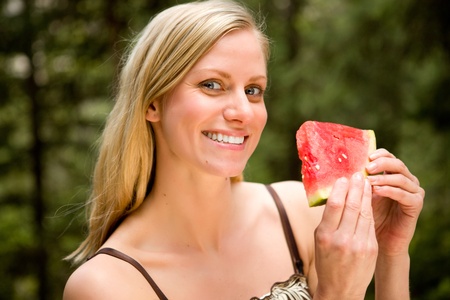 A portrait of a blonde woman eating a watermelonの写真素材