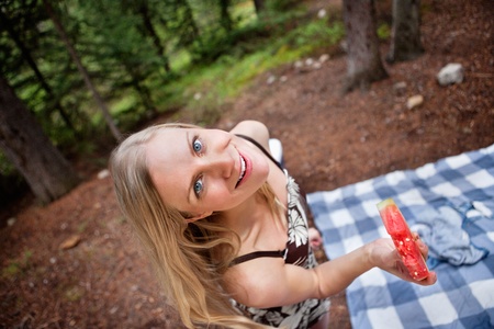 Top view of beautiful blond woman eating watermelon on picnicの写真素材
