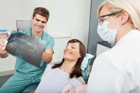 Smiling male dentist explaining the details of x-ray to a beautiful female patientの写真素材