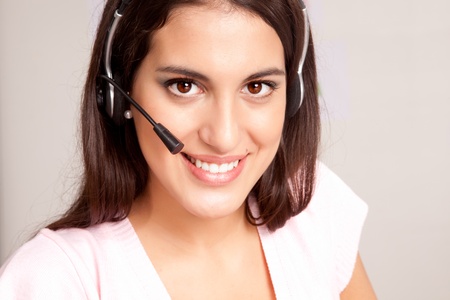 A female receptionist smiling at the viewer talking on the phoneの写真素材