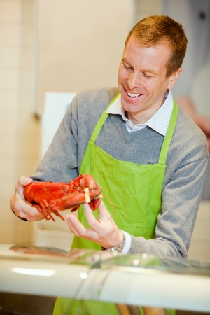 A grocery store worker with a lobster at the fish counterの写真素材