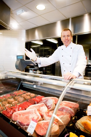 Portrait of a happy butcher welcoming customers to the shopの写真素材