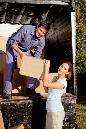 A happy couple moving boxes from a moving truckの写真素材