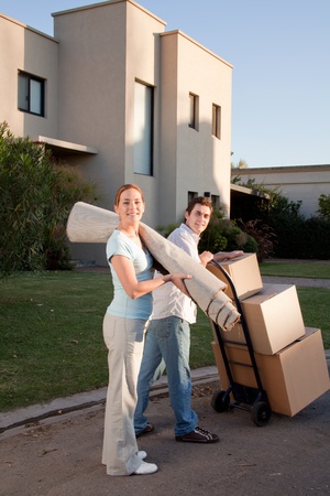 Portrait of a happy couple with moving boxes and small rugの写真素材