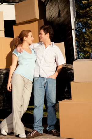 A happy couple in front of a moving van filled with cardboard boxesの写真素材