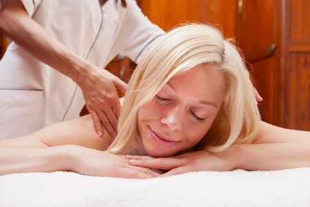 A beautiful young blonde woman receiving a shoulder massageの写真素材