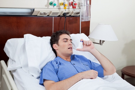 Asthmatic male patient on bed using asthma inhalerの写真素材