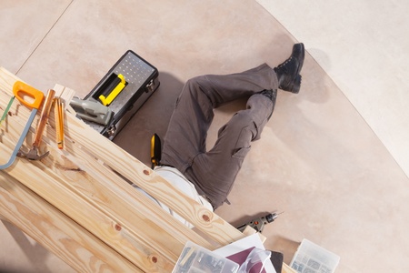 Carpenter working under the table with carpentry tools aroundの写真素材