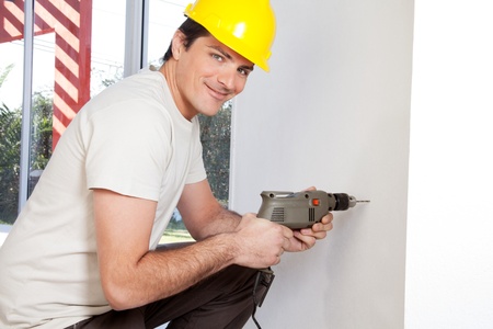 Portrait of smiling man worker with hard hat drilling wallの写真素材