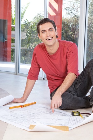 Portrait of happy smiling man pointing at blueprint of paperworkの写真素材