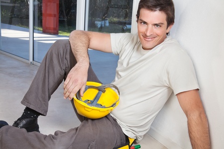 Portrait of young man sitting with construction helmetの写真素材