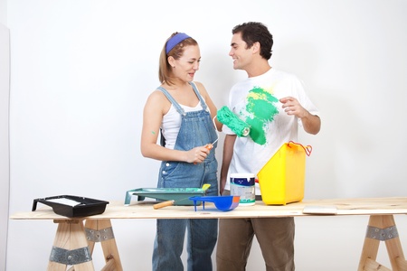 Smiling woman painting husband's t-shirt with rollerの写真素材