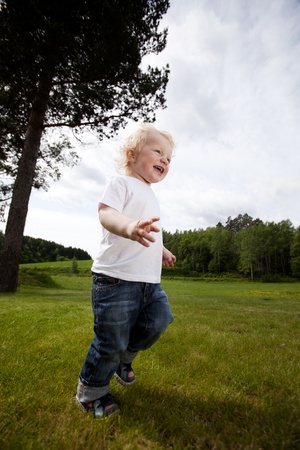 A young toddler boy running in an open grass area, excited and freeの写真素材