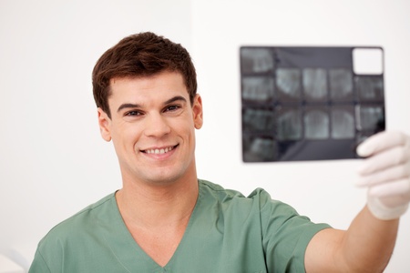 A smiling happy dentist holding x-rays, looking at the cameraの写真素材