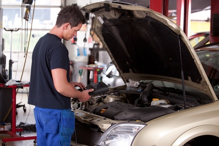 A young mechaing running a diagnostic test on a carの写真素材