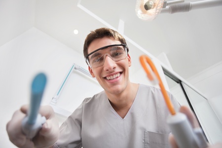 Close-up of young smiling dentist holding dental toolsの写真素材