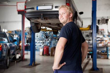 A happy smiling mechanic in an autio repair shop, looking at the cameraの写真素材
