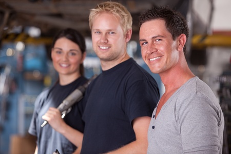 A group of three mechanics in a auto repair shop, looking at the cameraの写真素材