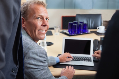 Portrait of mature man using laptop in office