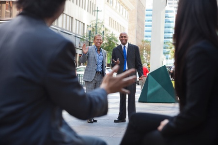 Business people waving and greeting friends on streetの写真素材