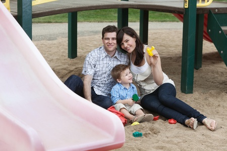 Portrait of happy couple sitting with their son in playgroundの写真素材