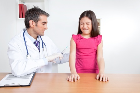 Doctor giving child patient injection in clinic の写真素材