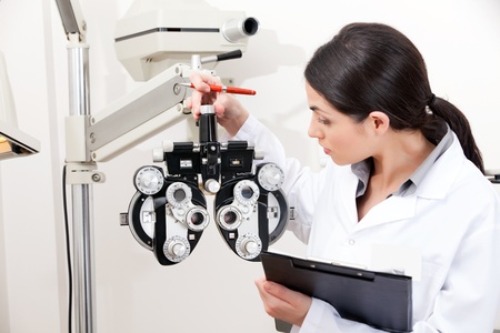 Female optometrist looking at phoropter の写真素材