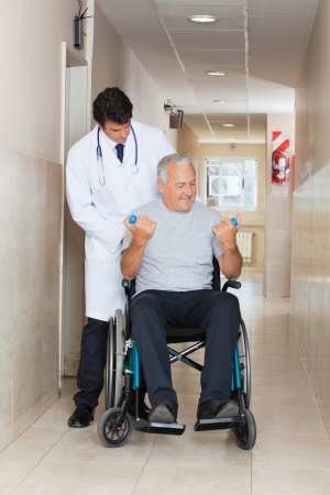 Doctor giving muscle training to the senior man sitting in a wheelchairの写真素材