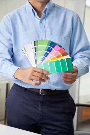 Midsection of male interior designer holding fanned out color swatchesの写真素材