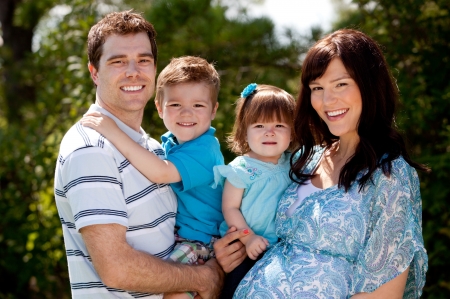 Outdoor portrait of a happy young family with pregnant motherの写真素材
