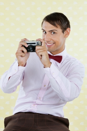 Portrait of male geek photographing through a retro camera over textured backgroundの写真素材