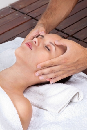 Beautiful young female receiving head massage by a male masseuse at health spaの写真素材