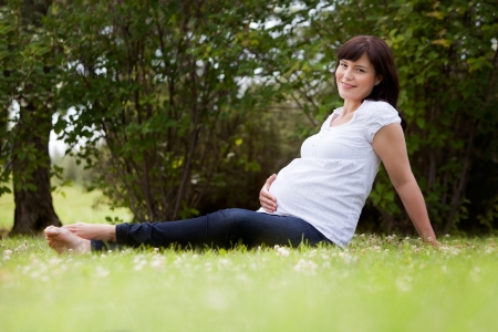 Portrait of a pregnant woman in third trimester relaxing in parkの写真素材