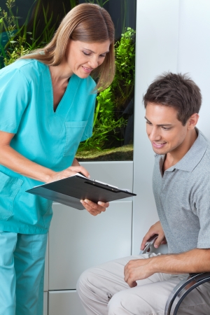 Female dentist taking an appointment of male patient on clipboard at clinicの写真素材