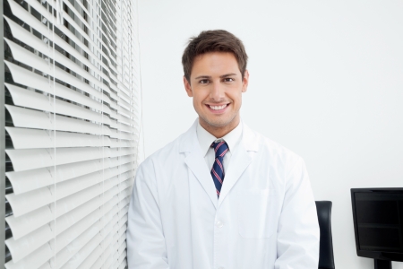 Portrait of happy young male dentist standing in clinicの写真素材