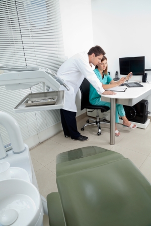 Doctor and female assistant in discussion with dentist chair in foregroundの写真素材